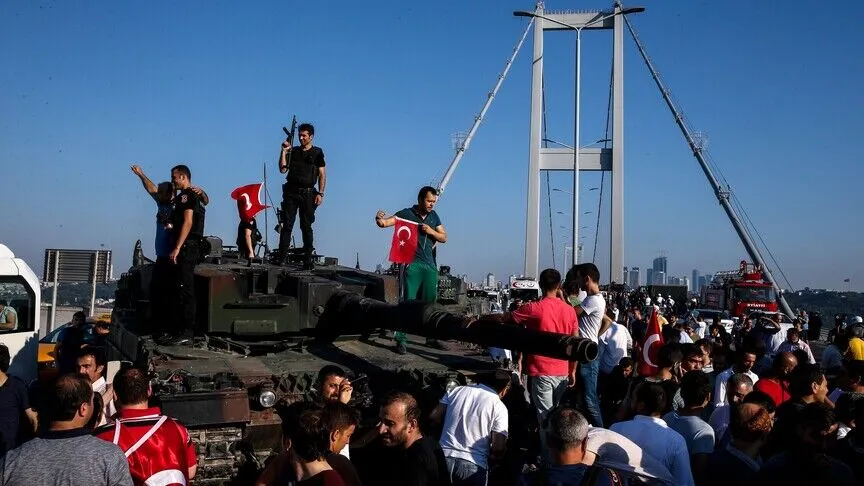 Crowds and police stand atop a tank abandoned by coup soldiers on İstanbul's Bosphorus bridge, waving Turkish flags, the morning after the July 2016 coup attempt.