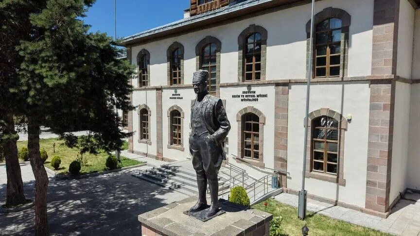 The Erzurum Congress building, a two-story stone building now a museum, with a statue of Mustafa Kemal Atatürk in military dress standing before it.
