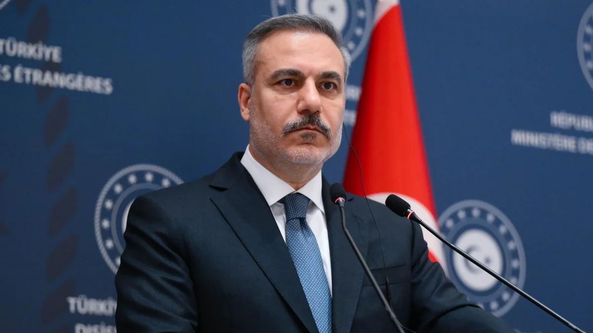 Foreign Minister Hakan Fidan at a lectern microphone in front of a dark blue Turkish Foreign Ministry backdrop and a Turkish flag.