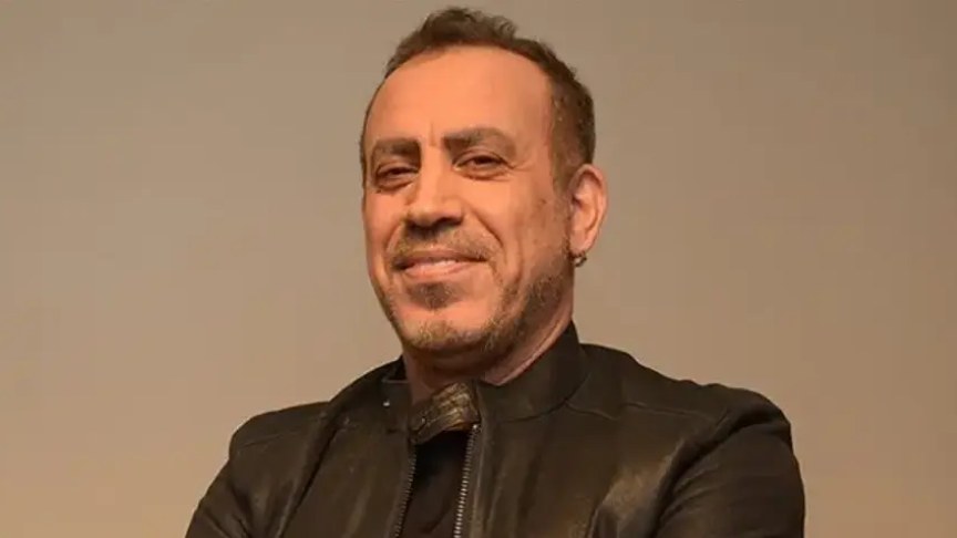 Haluk Levent, in a black leather jacket, looking at the camera against a plain background.