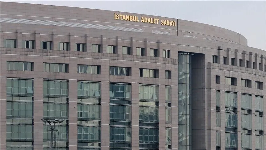 The upper facade of the İstanbul Justice Palace, a long stone building with rows of windows and gold lettering reading İstanbul Adalet Sarayı along the curved roofline.