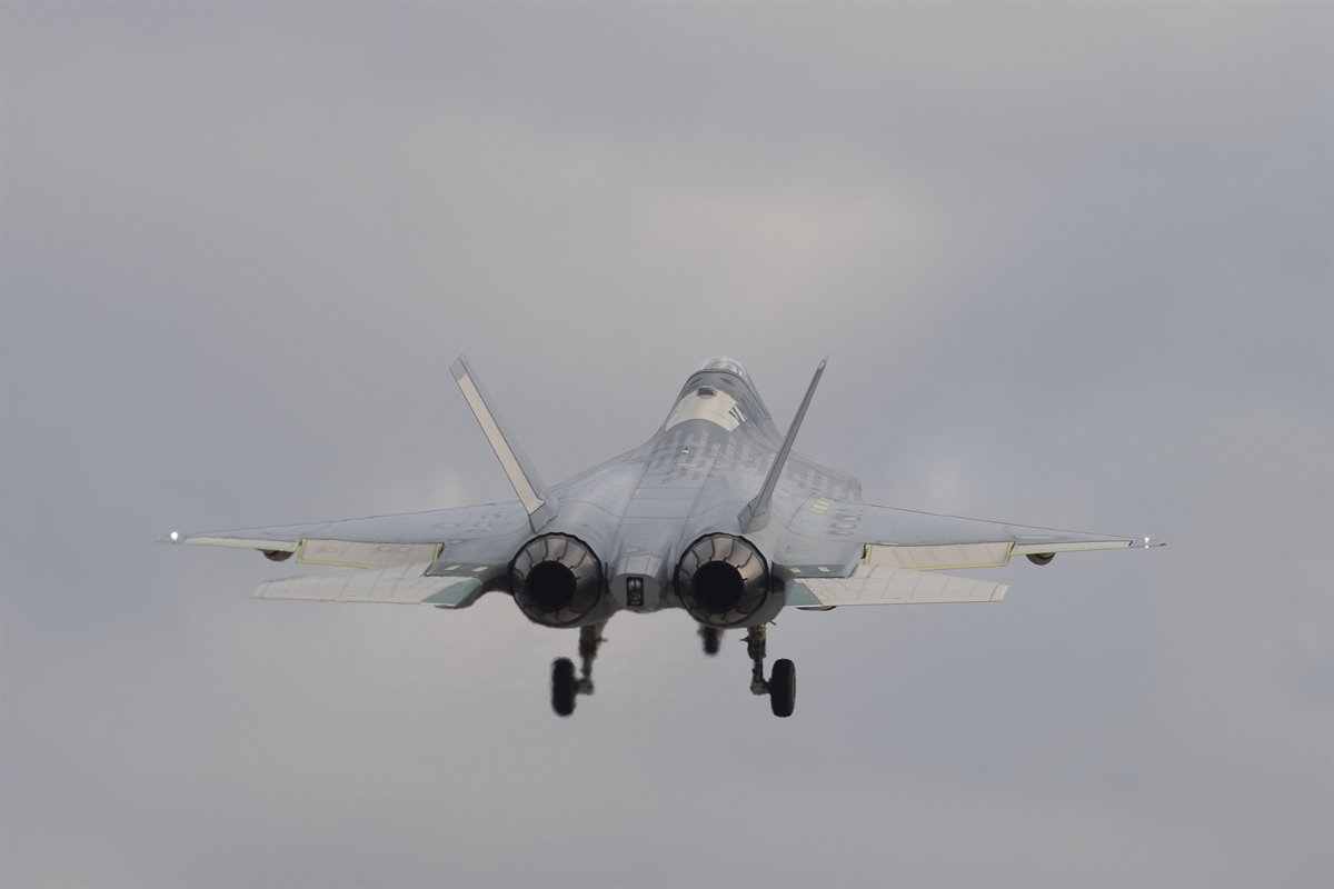 The KAAN fighter prototype climbs out with its landing gear down, seen from behind so both engine nozzles face the camera.